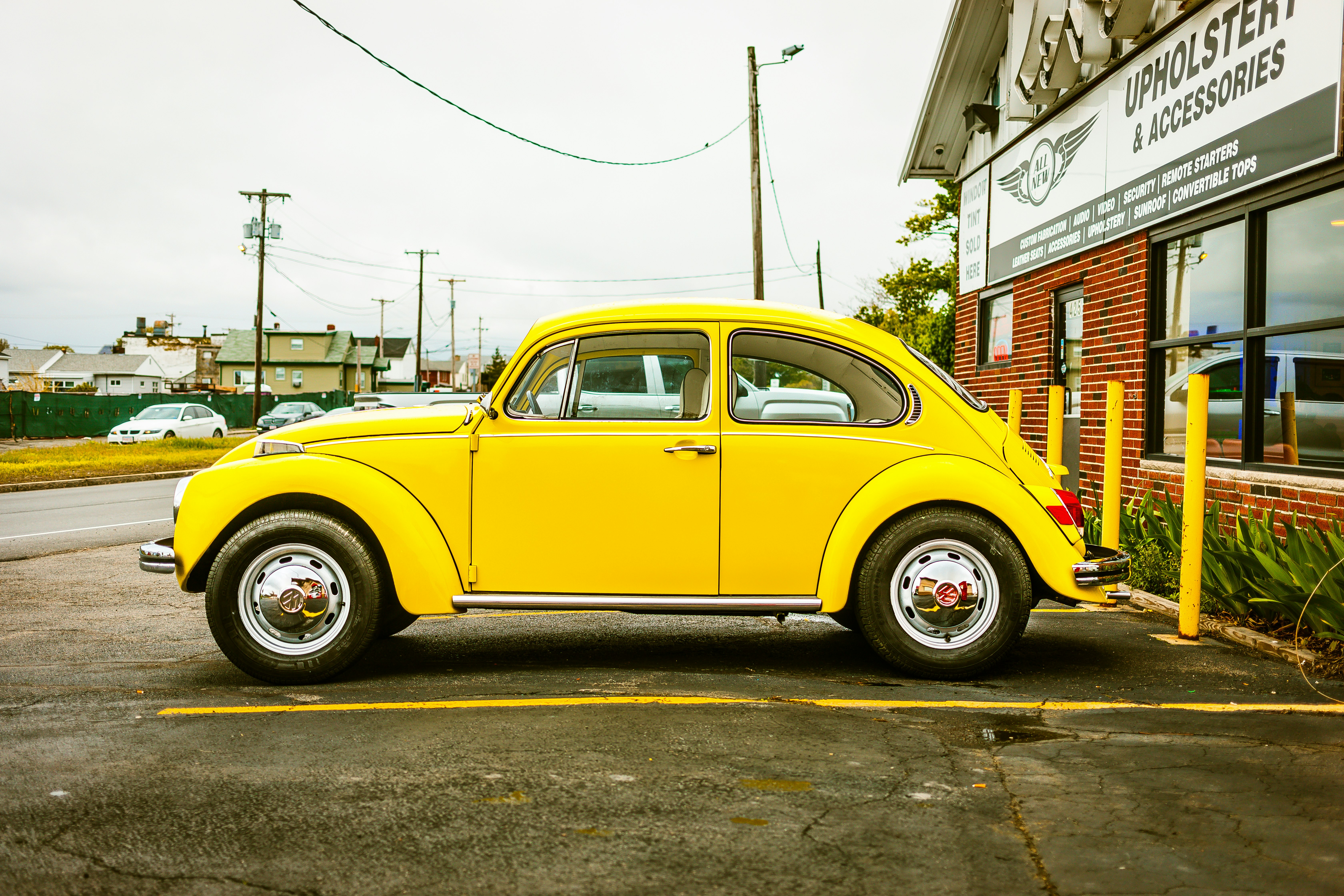 yellow Volkswagen Beetle coupe parked near building
